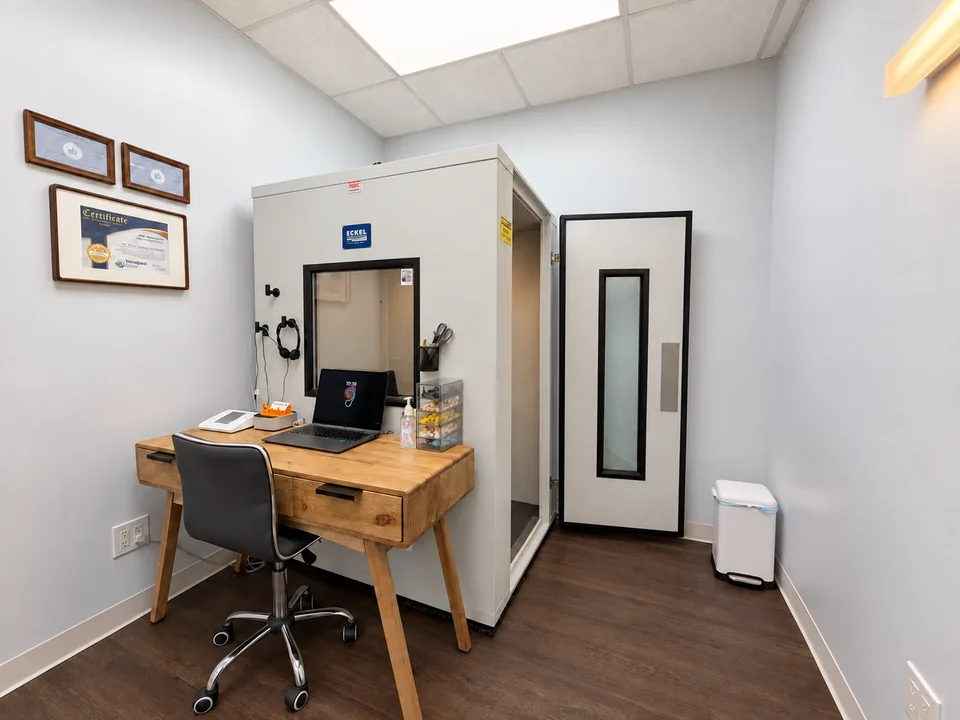 Pinnacle Audiology’s audiometric suite with an open testing-booth door and audiologist’s workstation